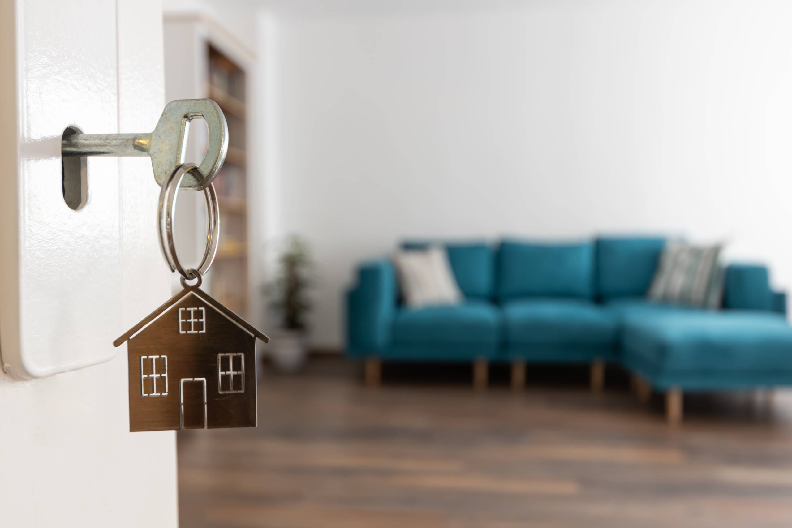 Open door to a new home. Door handle with key and home shaped keychain. Mortgage, investment, real estate, property and new home concept